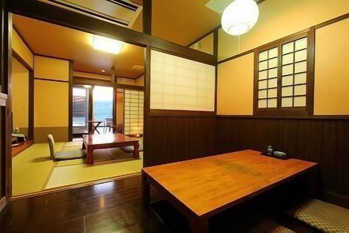 Ein traditioneller japanischer Raum mit Tatami-Boden, einem niedrigen Holztisch und Schiebetüren.