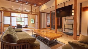 Una habitación de estilo japonés tradicional con suelo de tatami, una mesa de madera baja y un televisor montado en la pared.