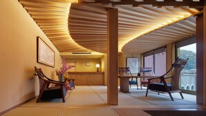 Un interior tradicional con suelo de tatami, mobiliario de madera y una estructura de techo curva.