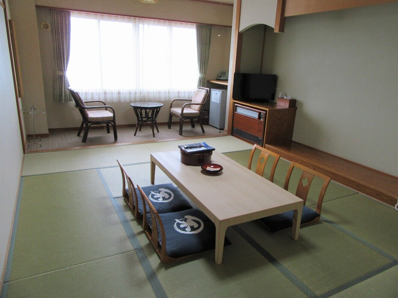 Ein traditioneller japanischer Raum mit Tatami-Böden, einem niedrigen Tisch und Sitzgelegenheiten.