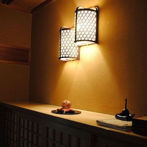 A wall-mounted light fixture with a geometric pattern, a small decorative item on a ledge, and a book or menu on the ledge. - Shinkanou Gourmet Ryokan (Izunokuni)