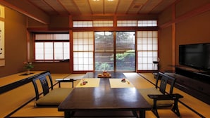 A traditional Japanese room with tatami flooring, a low table, and a television. - Shinkanou Gourmet Ryokan (Izunokuni)