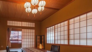 A traditional Japanese room with tatami flooring, a low table, a chair, and a sliding door. - Shinkanou Gourmet Ryokan (Izunokuni)