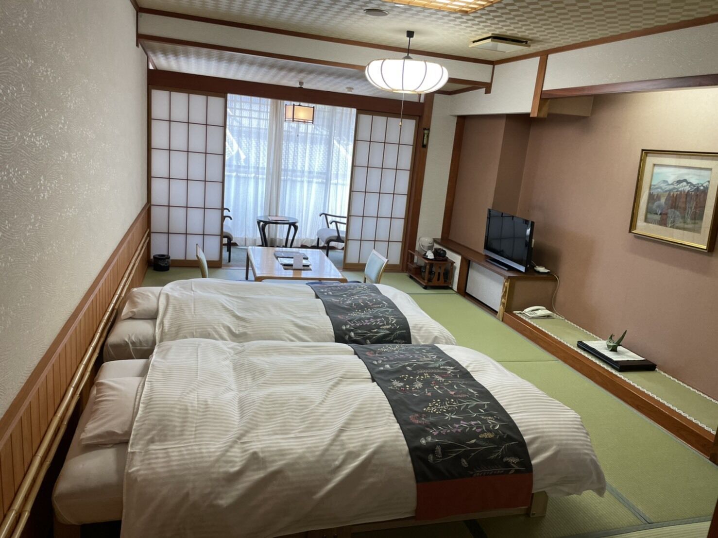 Hotellihuone, jossa on kaksi sänkyä, televisio, työpöytä ja perinteinen japanilainen liukuovi.
