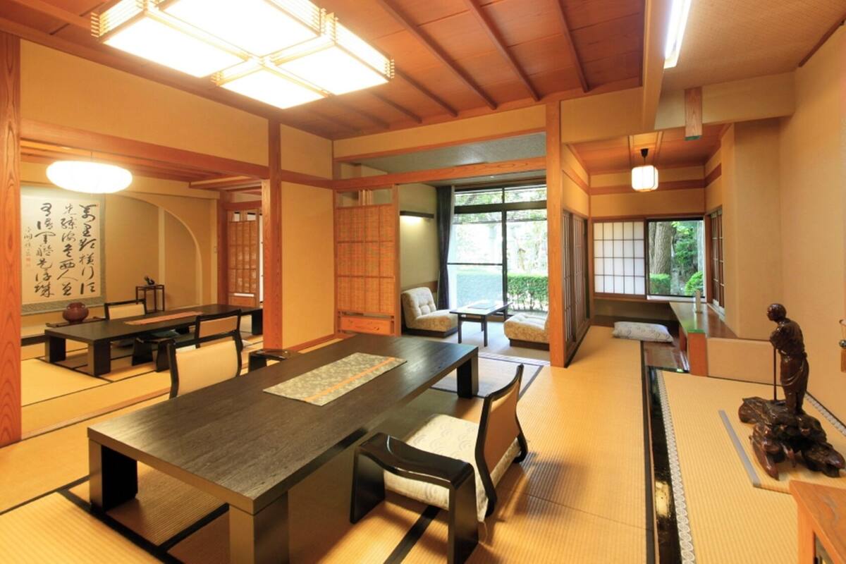 A traditional Japanese room with tatami flooring, a low table, chairs, and sliding doors.