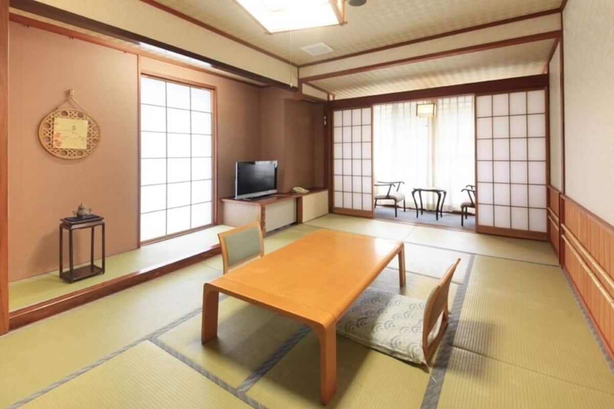 A traditional Japanese room with tatami flooring, a low table, a television, and sliding doors.