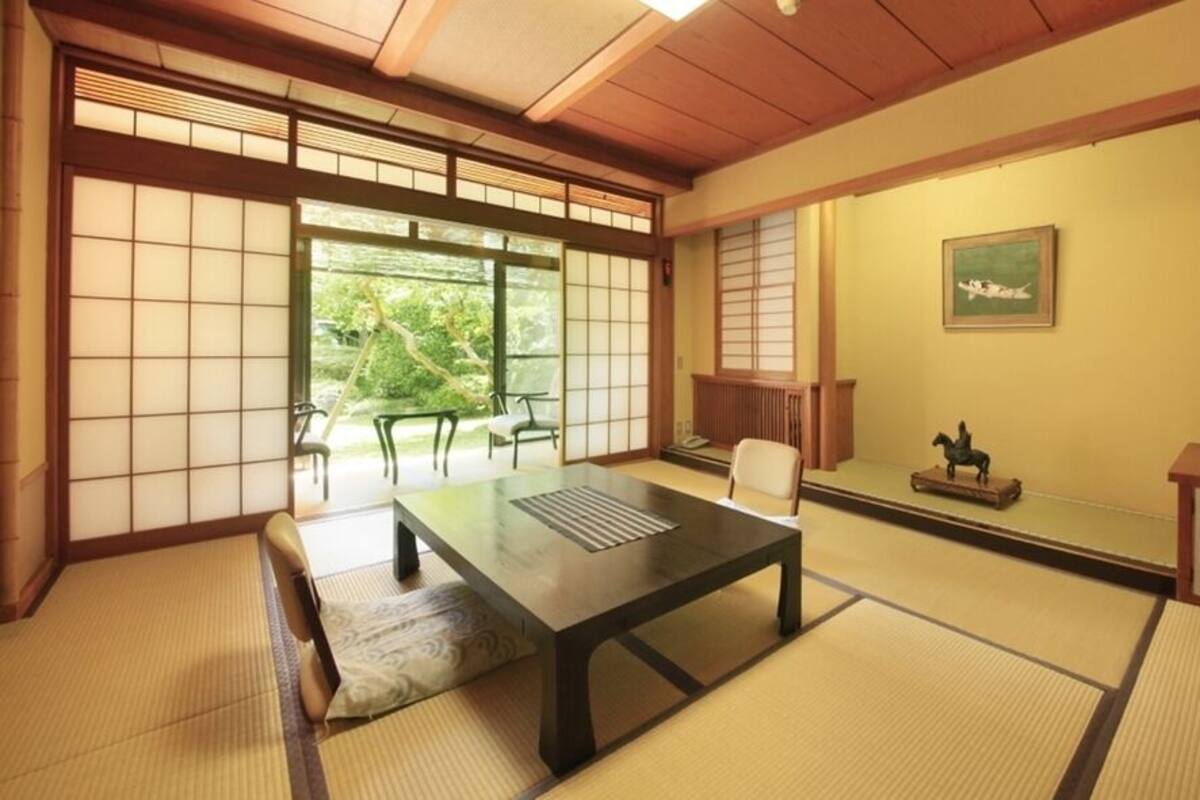 A traditional Japanese room with tatami flooring, a low table, a chair, a cabinet, and a sliding door.