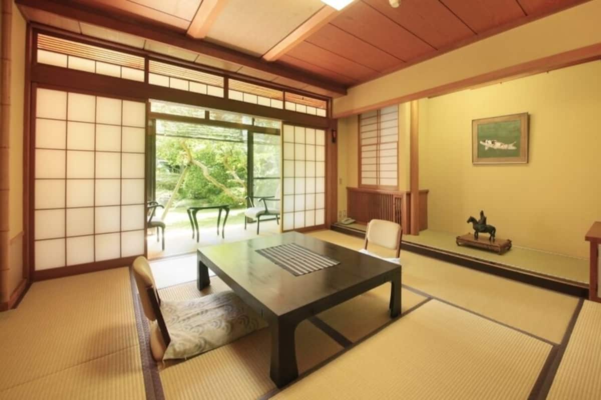 Perinteinen japanilainen huone, jossa on tatamimatto, matala pöytä, tuoli, kaappi ja liukuovi.