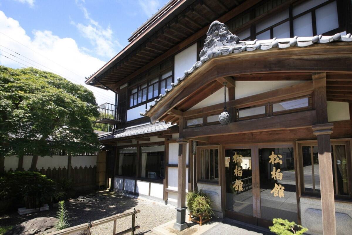 A traditional Japanese building with a wooden structure, a tiled roof, and a small garden area.