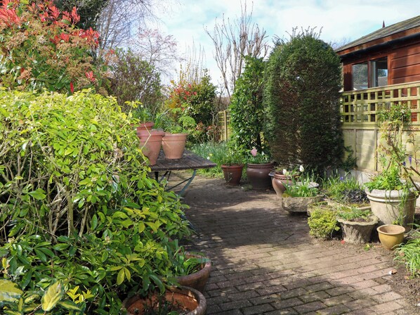 A garden pathway with potted plants and a wooden table. - Felix Cottage (Canterbury)