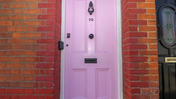 A pink door with the number 70, a black doorbell, and a black door with the number 68.