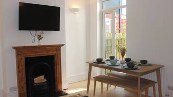 Una habitación con chimenea, una mesa de comedor con cuencos, un banco y un televisor montado en la pared.