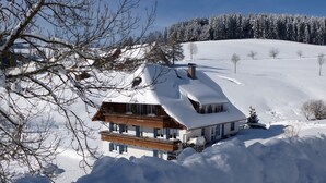 Una casa cubierta de nieve con un balcón de madera, rodeada por un paisaje nevado.