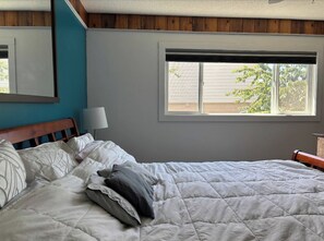 Um quarto com uma cama, uma janela e um abajur.