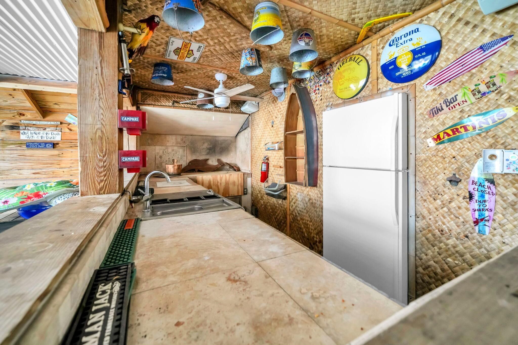 Ein schmaler Flur mit Holzboden, Deckenventilator und Kühlschrank.