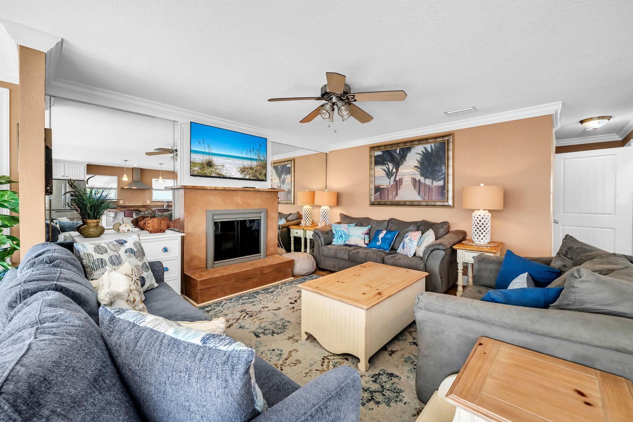 A living room with a fireplace, sofas, a coffee table, and a ceiling fan.