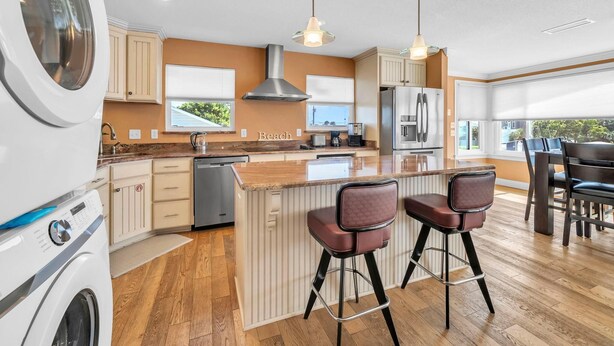 Una cocina moderna con una isla central, taburetes de bar y lavadora integrada.