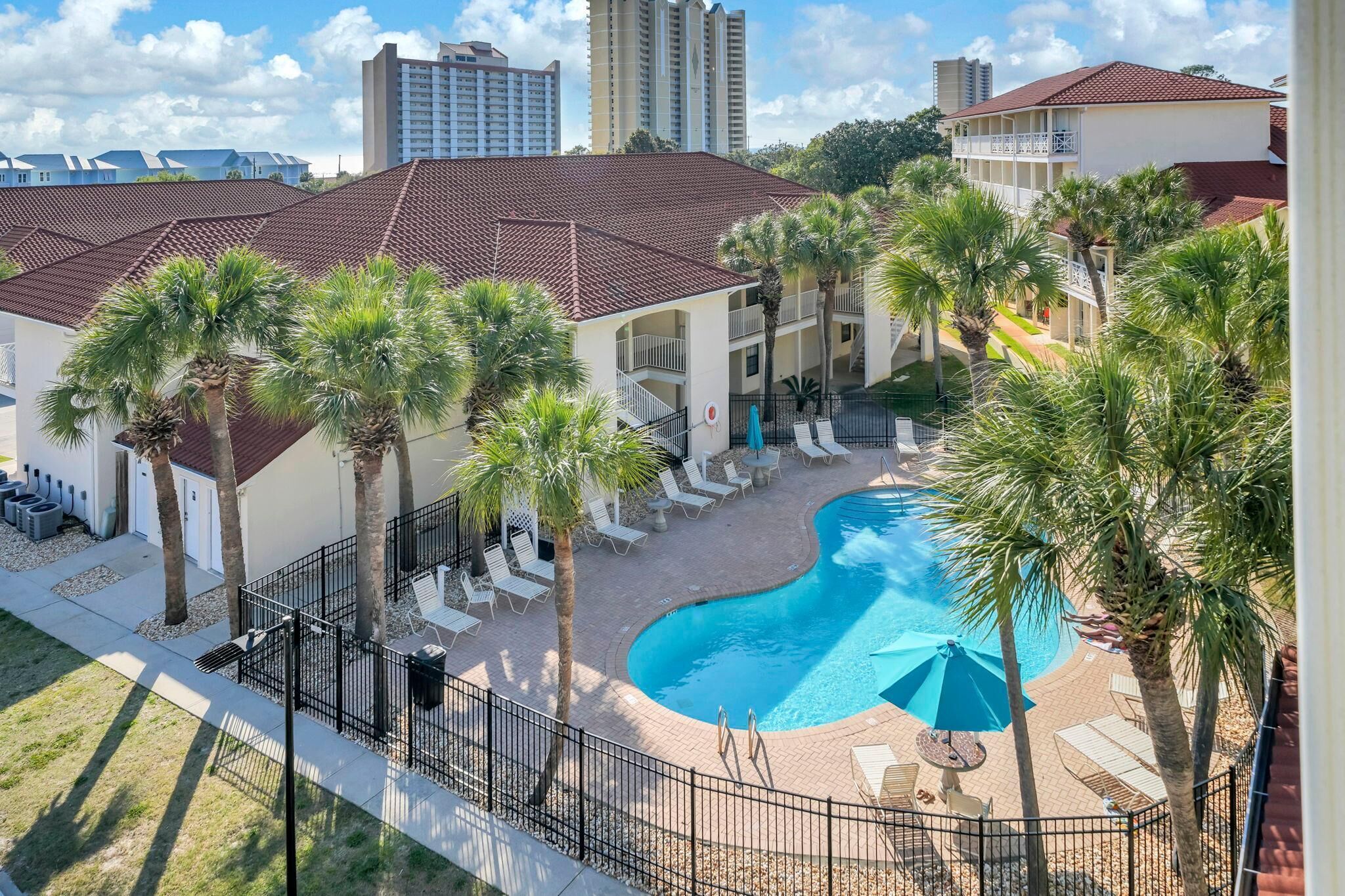 Un hotel con piscina, palmeras y vistas a altos edificios.