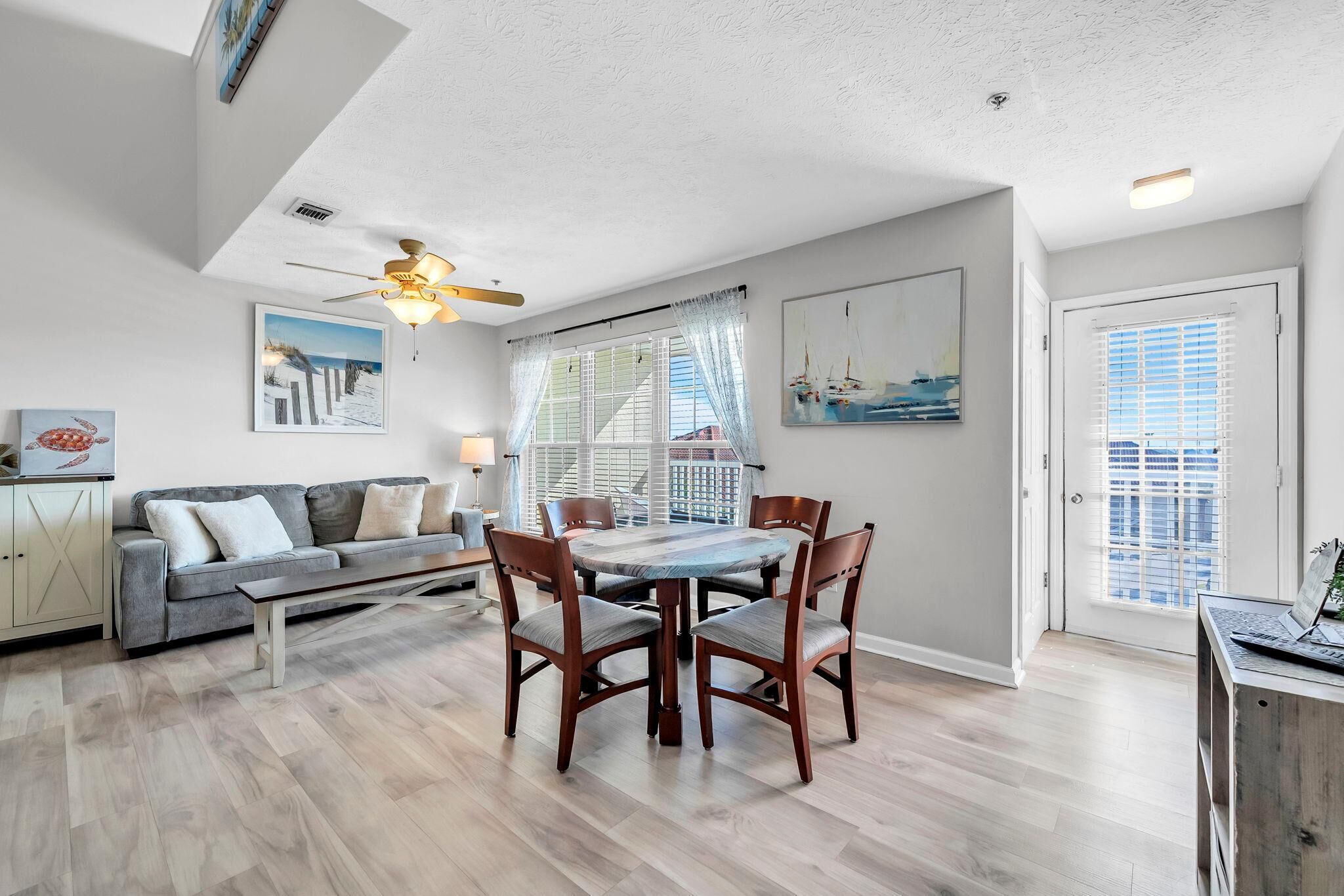 A dining area with a table and chairs, a sofa, and a ceiling fan.