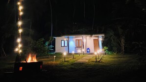 A small, single-story building with a porch, a fire pit, and a palm tree with lights. - Cozy 1-bedroom villa in awesome Tangalle with AC (Tangalle)