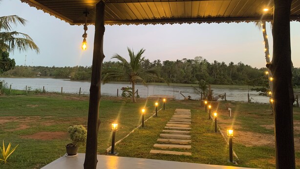 A covered outdoor area with a pathway leading to a body of water, surrounded by greenery and palm trees. - Cozy 1-bedroom villa in awesome Tangalle with AC (Tangalle)