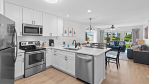 A modern kitchen with stainless steel appliances, a central island, and a dining area with a view. - Maravilla 3108 (Miramar Beach)