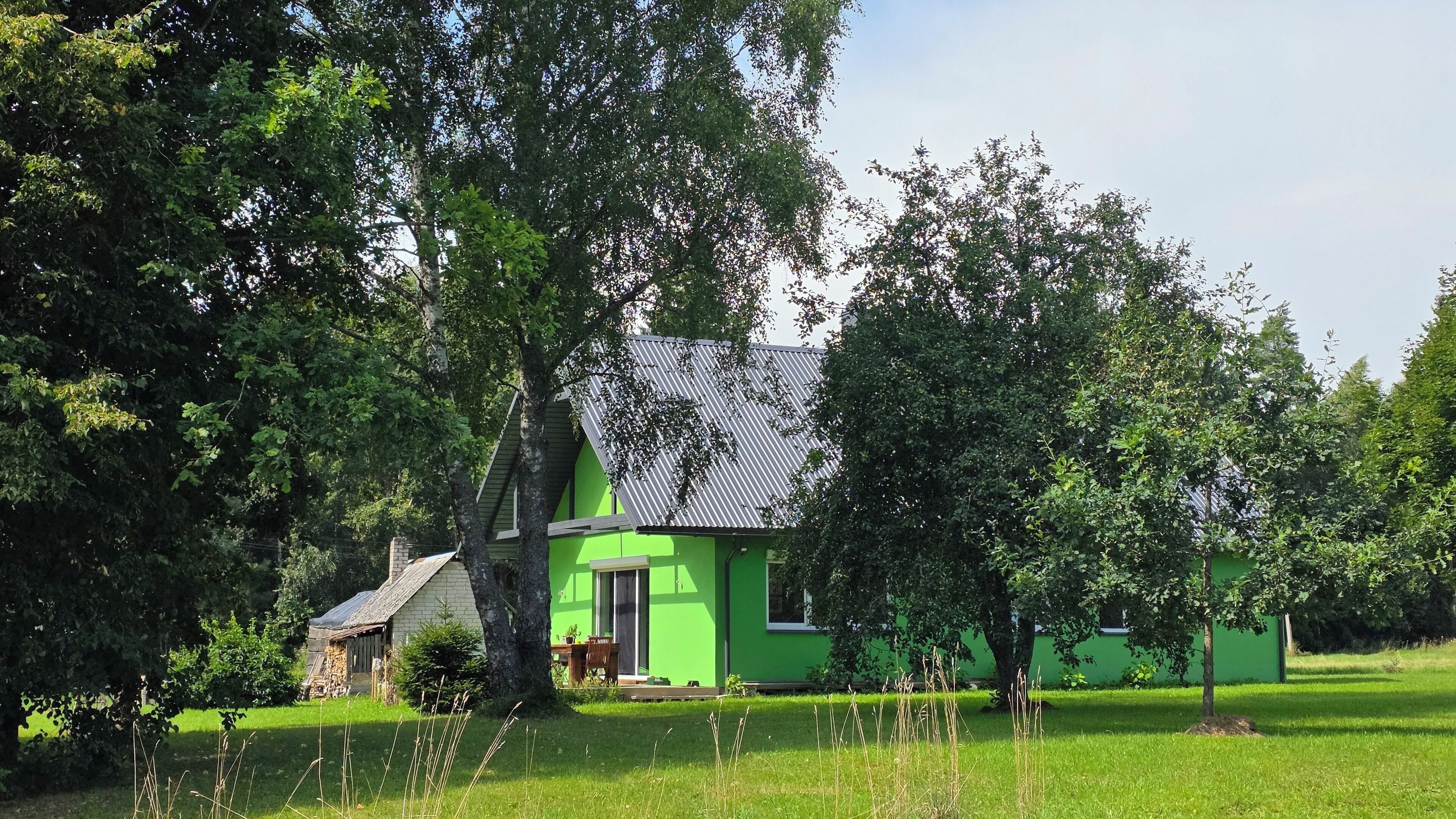 A house with a green exterior, surrounded by trees and grass.