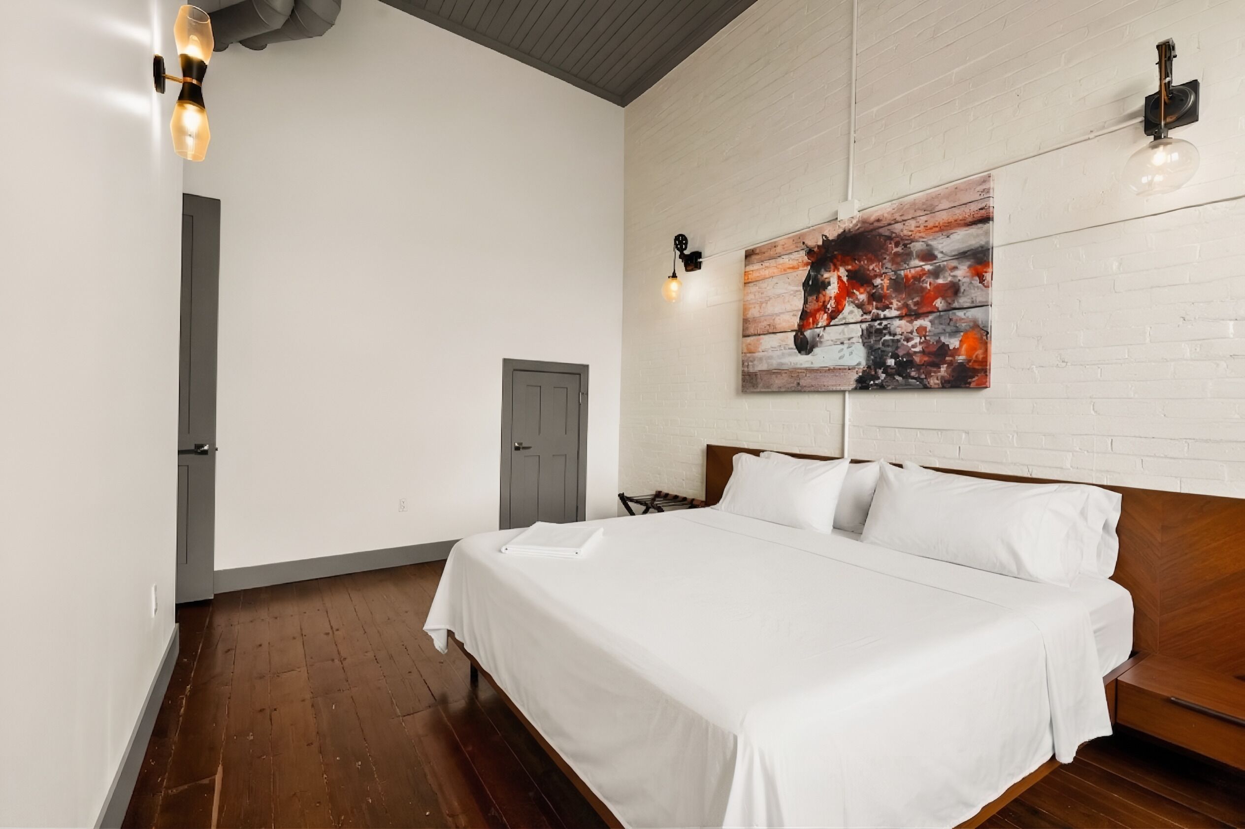 A bedroom with a large bed, a wooden headboard, a white wall, and a door.