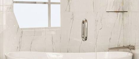 A modern bathroom with a freestanding bathtub, marble walls, and a window.