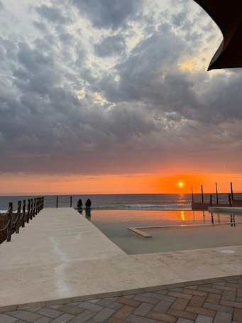A beachside walkway with a view of the ocean and sunset.