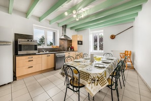 A kitchen with a dining table, chairs, and a window. - Gîte "Domaine de Collonges" with Private Terrace and Garden (Saint-Georges-de-Baroille)