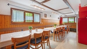 A dining area with wooden paneling, tables with white tablecloths, and chairs with cushions.