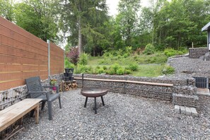 Une terrasse extérieure avec un banc en bois, un barbecue en métal et un mur en pierre.