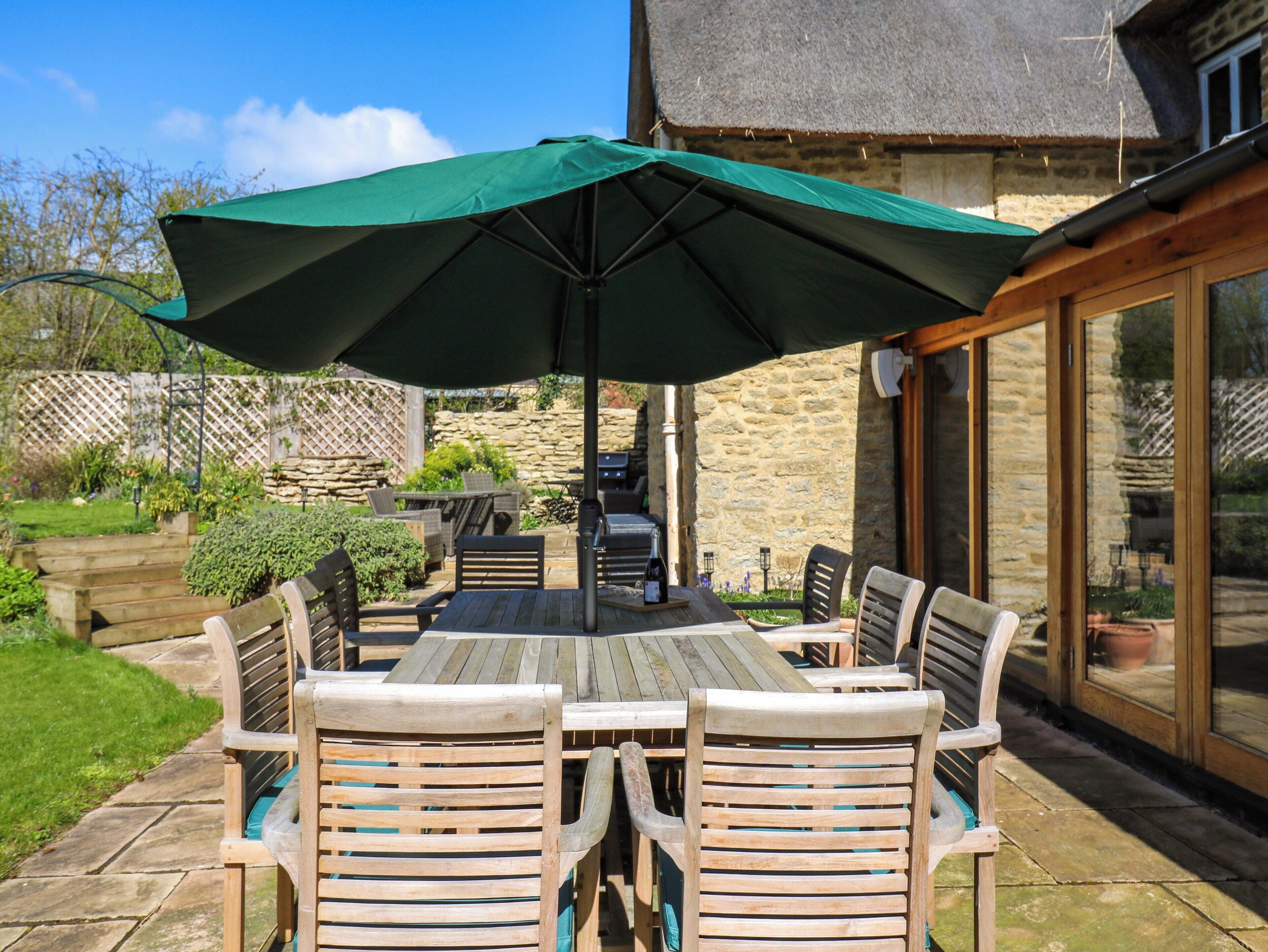 A patio with a table and chairs, a grill, and a stone wall.