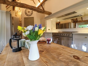 A wooden table with a white pitcher of flowers, a black lantern, and a jar of jam. - Manor Farm Cottages (Milton Keynes)