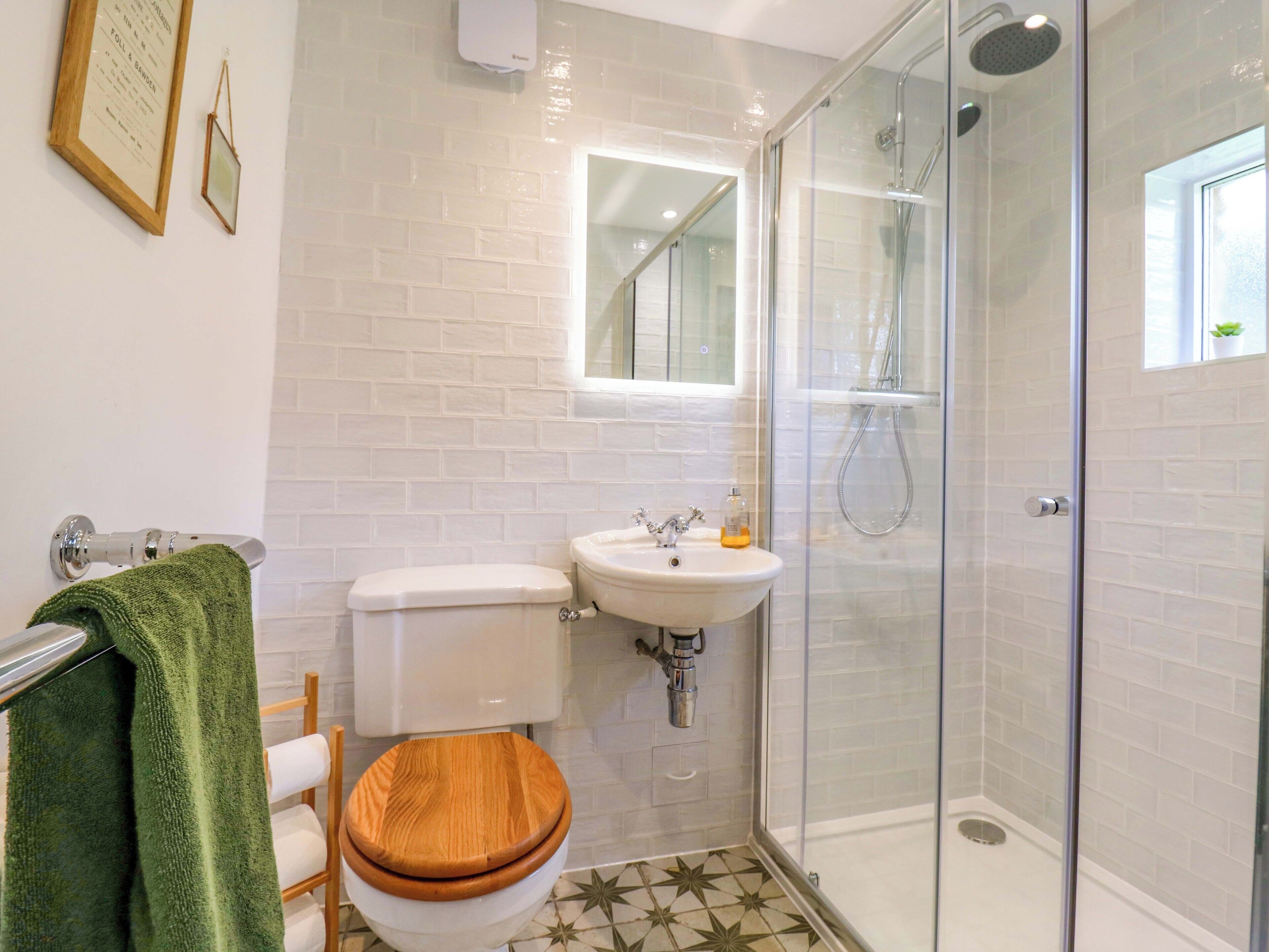 A bathroom with a toilet, sink, shower, and a mirror.
