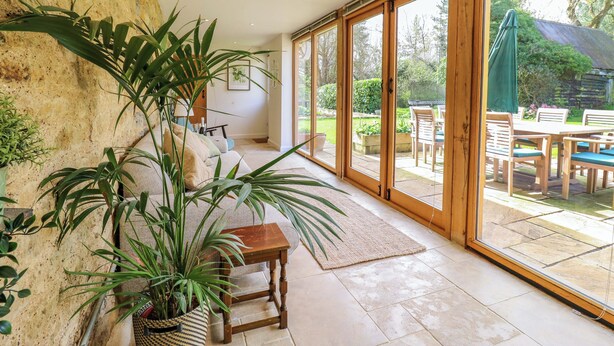 A spacious room with a large sliding glass door leading to an outdoor patio area. - Manor Farm Cottages (Milton Keynes)