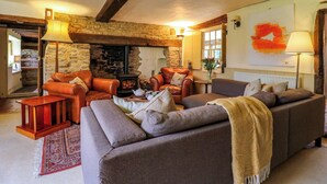 A cozy living room with leather sofas, a fireplace, and a stone wall. - Manor Farm Cottages (Milton Keynes)
