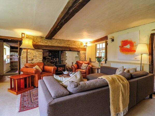 A cozy living room with leather sofas, a fireplace, and a stone wall.
