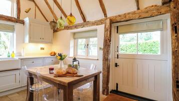 Une cuisine rustique avec des poutres en bois, une table à manger avec des chaises, une fenêtre donnant sur un beau paysage et une porte.