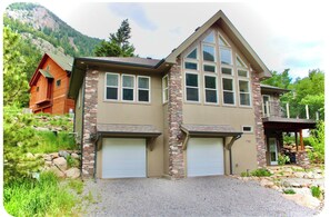 A two-story house with a stone facade, two garage doors, and a balcony.