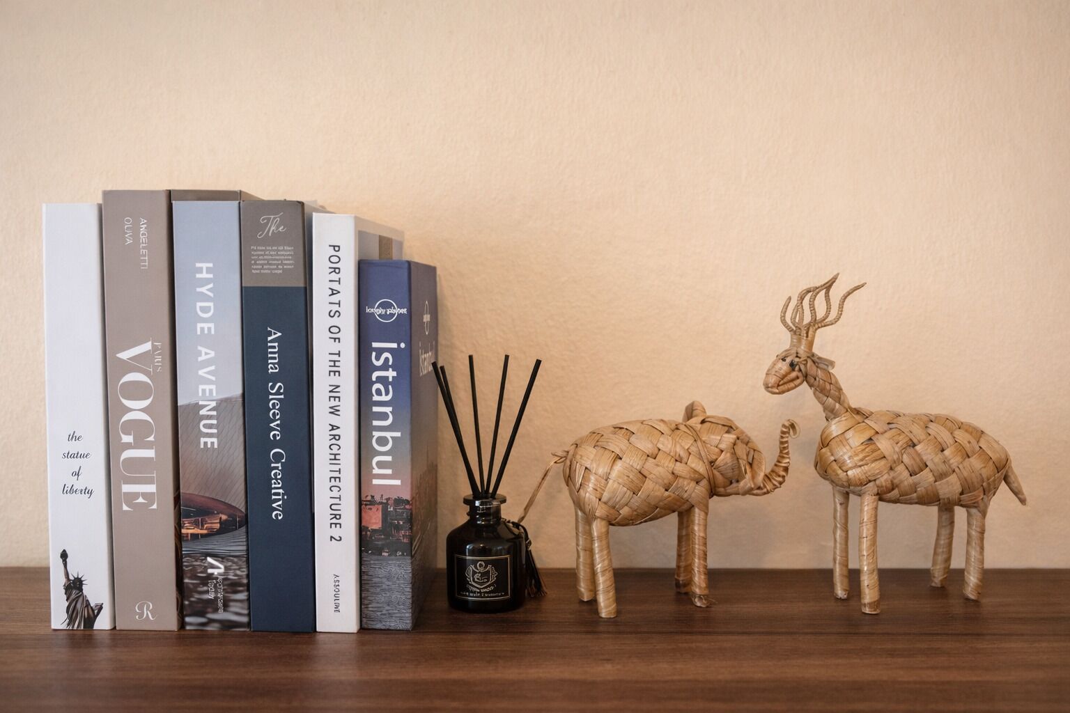 Ein Bücherregal mit Büchern, einem Schilferdiffusor und zwei gewebten Tierfiguren.
