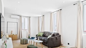 Una sala moderna con un sofá gris, una mesa de centro redonda y un reposapiés a rayas.