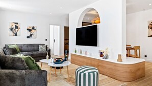 Una sala de estar moderna con un sofá, una mesa de centro y un televisor montado en una pared blanca.