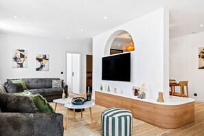 Un salon moderne avec un canapé, une table basse et un téléviseur fixé au mur, qui est de couleur blanche.