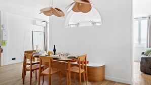 Un comedor moderno con una mesa redonda, sillas de madera e iluminación colgante.