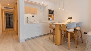 Une cuisine moderne avec des meubles blancs, un four à micro-ondes et un coin repas comprenant des chaises et une table en bois.