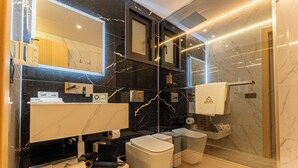 Une salle de bain moderne avec un grand miroir, des murs en marbre, des toilettes et un espace douche.