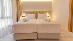 Un lit double avec une tête de lit, deux tables de chevet et une grande fenêtre avec des rideaux.