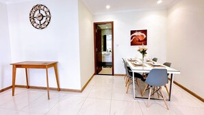 Zona pranzo con tavolo e sedie in legno, una sveglia a parete e un quadro.